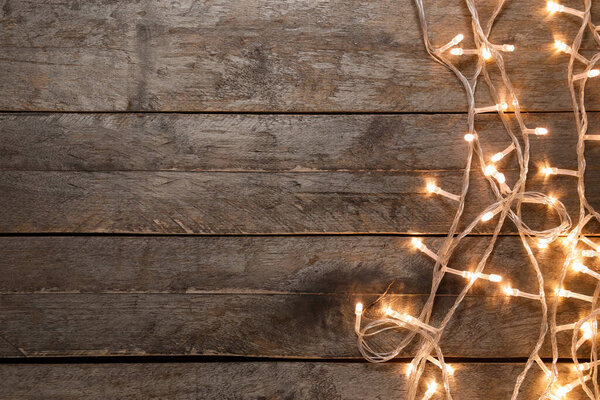 Glowing Christmas lights on dark wooden background