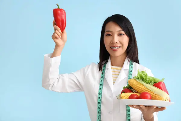 Vrouwelijke Aziatische Voedingsdeskundige Met Groenten Blauwe Achtergrond — Stockfoto