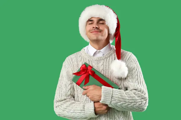 Щасливий Молодий Чоловік Капелюсі Санта Подарунковою Коробкою Зеленому Фоні — стокове фото