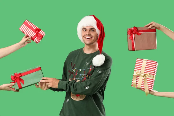 快乐的年轻人戴着圣诞礼帽手拿着绿色背景的礼品盒 — 图库照片