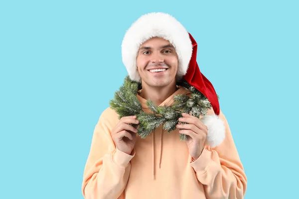 Happy Young Man Santa Hat Christmas Wreath Blue Background — Stock Photo, Image