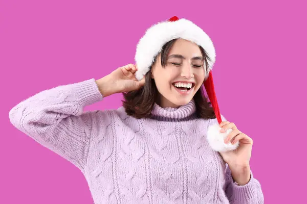Mor Arka Planda Noel Baba Şapkalı Mutlu Güzel Kadın — Stok fotoğraf