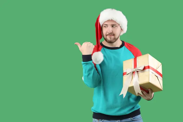 Jeune Homme Chapeau Santa Avec Boîte Cadeau Pointant Quelque Chose — Photo
