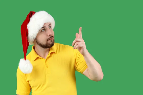 Noel Baba Şapkalı Genç Adam Yeşil Arka Plandaki Bir Şeyi — Stok fotoğraf