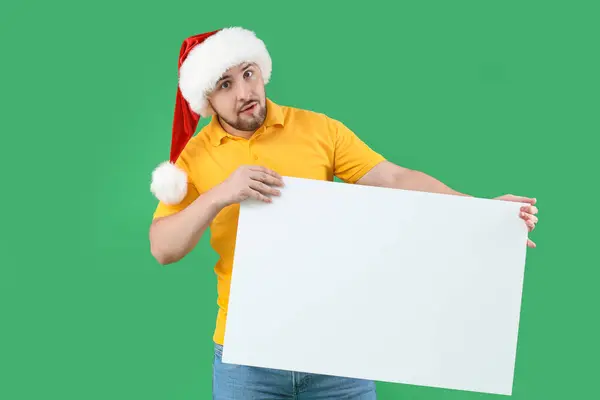 Mladý Muž Santa Klobouk Prázdným Plakátem Zeleném Pozadí — Stock fotografie