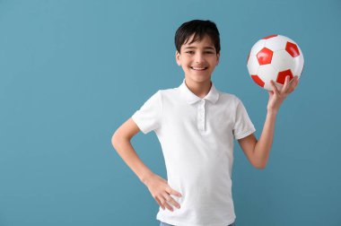 Mavi arka planda futbol topu olan küçük çocuk.