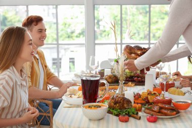 Genç adam Şükran Günü 'nde arkadaşlarıyla yemek masasına lezzetli hindi getiriyor.