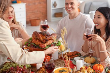 Bir grup genç arkadaş Şükran Günü 'nde hindiyle yemek yiyor.