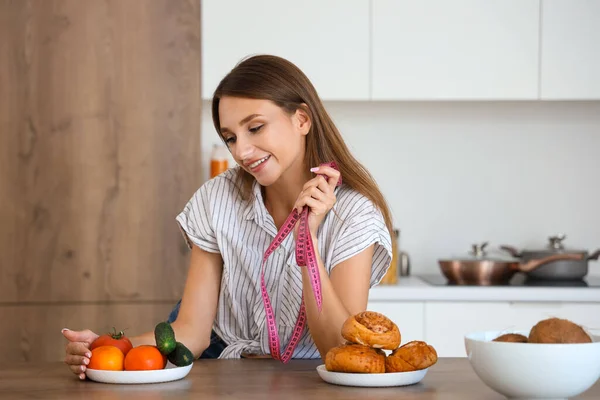 Młoda Kobieta Taśmą Pomiarową Wyboru Między Zdrowym Niezdrowym Jedzeniem Kuchni — Zdjęcie stockowe