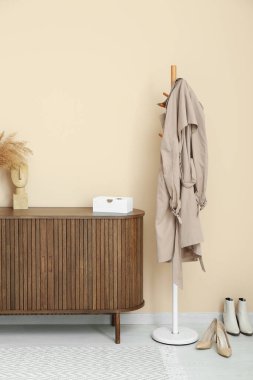 Koridordaki bej duvarın yanında çekmeceler ve askılar.