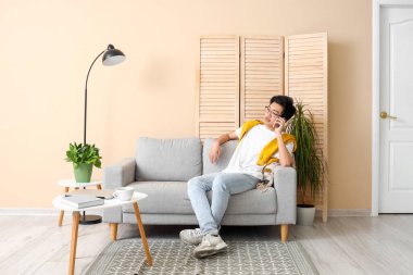 Asyalı genç adam izin gününde cep telefonuyla konuşuyor.