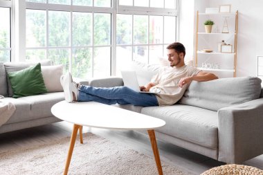 Genç adam izin gününde dizüstü bilgisayar kullanıyor.