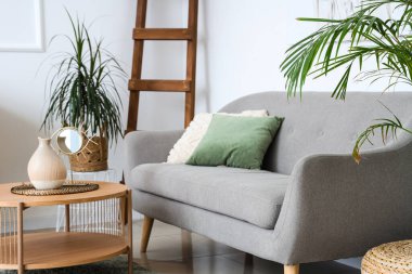 Kanepesi, masası ve çiçekleri olan bir oturma odası.