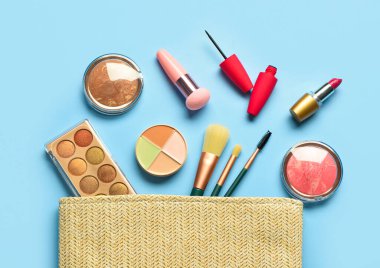 Mavi arka planda farklı dekoratif kozmetik ürünleri olan bir çöp torbası.