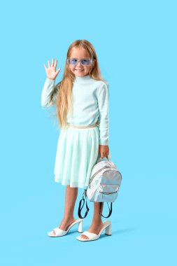 Mavi arka planda topuklu küçük şirin kız.