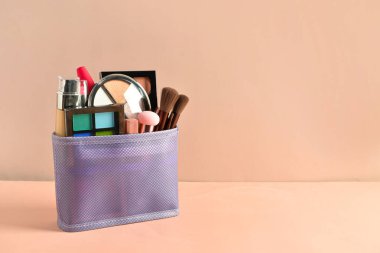 Pembe arka planda dekoratif makyaj malzemesi olan çanta.
