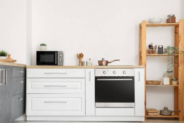 Beyaz tezgahlı ve raf üniteli aydınlık mutfağın içi.