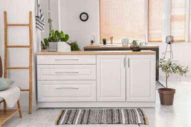 Beyaz tezgahlı ve çizgili halılı aydınlık mutfağın içi.