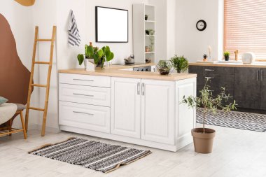 Beyaz tezgahlı ve çizgili halılı aydınlık mutfağın içi.