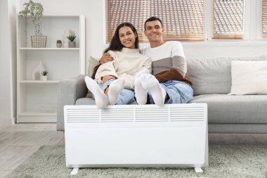 Genç çift kaloriferde ısınıyor.