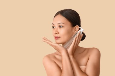 Bej arka planda bir şişe mikiler suyu olan genç Asyalı kadın, yakın plan.