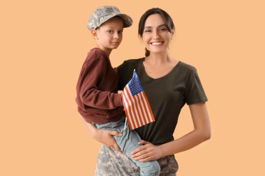 Amerikan bayrağı taşıyan küçük bir çocuk ve bej arka planda askeri annesi. Gaziler Günü kutlamaları