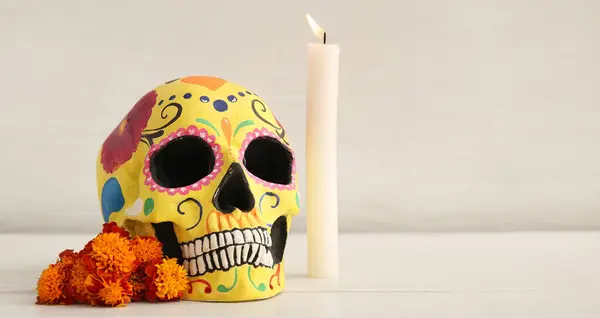 Painted skull, candle and marigold flowers on light background with space for text. Celebration of Mexico\'s Day of the Dead (El Dia de Muertos)