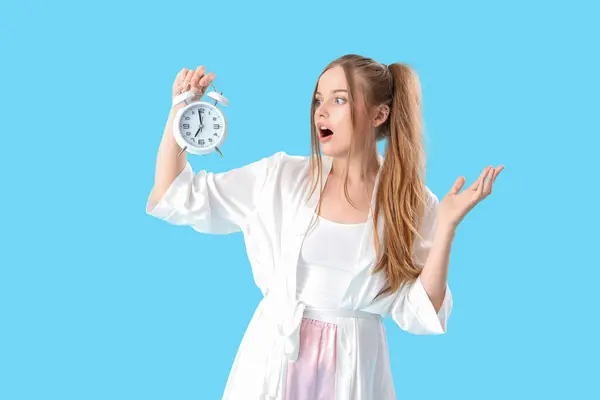 青い背景に目覚まし時計が付いている驚いた若い女性 — ストック写真
