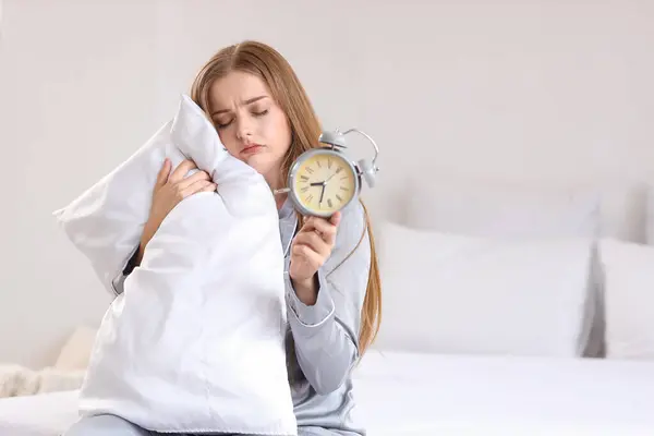 自宅でベッドの目覚まし時計を持つ眠っている若い女性 — ストック写真