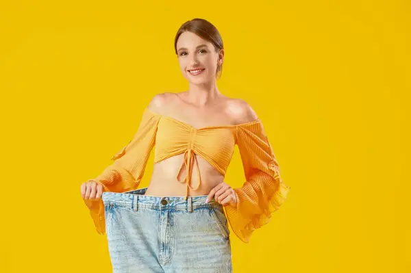 Mulher Bonita Jeans Soltos Fundo Amarelo Conceito Perda Peso — Fotografia de Stock