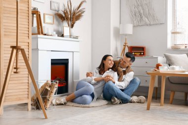 Evde şöminenin yanında el ele tutuşan genç çift.