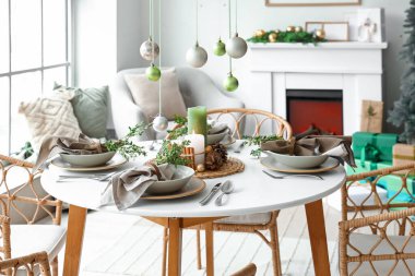 Noel sofrasında asılı duran toplar, yanan mumlar ve oturma odasında kozalaklar.