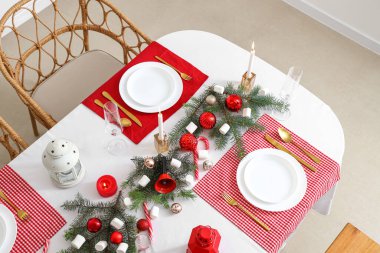 Kırmızı masa örtüsü, mumlar, şekerlemeler ve Noel süslemeleri olan şenlik masası.