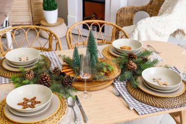 Köknar ağacı dalları, çam kozalakları, tabaklar ve çatal bıçaklarla Noel sofrası.