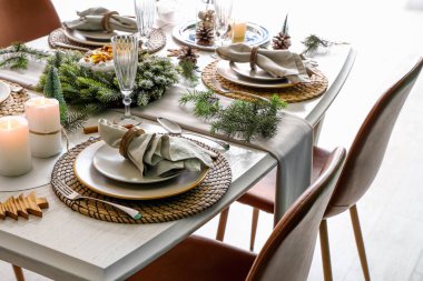 Katlanmış peçeteler, tabaklar, çatal bıçak takımı ve köknar dallarıyla Noel sofrası.