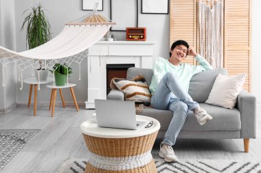 Genç Asyalı adam izin gününde evinde dinleniyor.