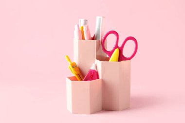 Pembe arka planda farklı kırtasiye malzemesi olan tutucu