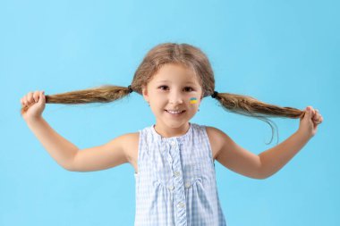 Yüzünde mavi arka planda Ukrayna bayrağı olan mutlu küçük bir kız.