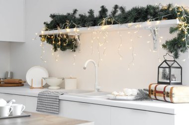 Parlayan ışıkları ve rafında köknar ağacı dalları olan festival mutfağı. Noel kutlaması