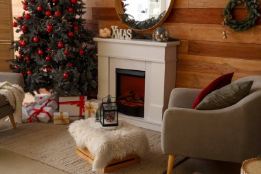 Noel ağacı, şömine ve koltuğu olan şenlikli bir oturma odası.