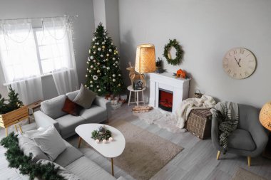 Noel ağacı, şömine ve kanepeleri olan şenlikli bir oturma odası.