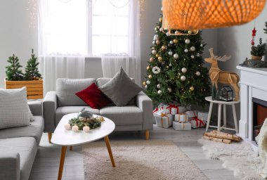 İçinde Noel ağacı olan, sehpada ve koltuklarda mum yakan şenlikli bir oturma odası.