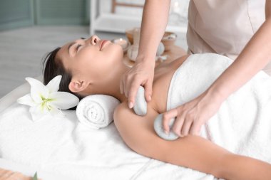 Kaplıcada taşlarla tedavi gören genç bir kadın.