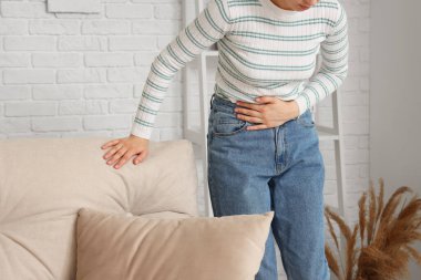 Evde karın ağrısı çeken genç bir kadın.