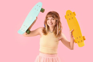 Pembe arka planda kaykay yapan genç bir kadın.