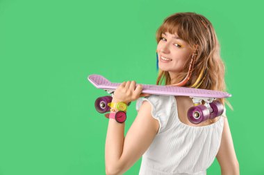Yeşil arka planda kaykaylı genç bir kadın.