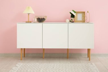 Lambalı beyaz dolap ve pembe duvarın yanında Noel süsü