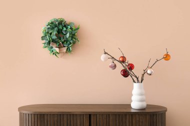 Bej duvarın yanında Noel dekoru olan ahşap dolap.