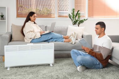 Genç çift kaloriferin yanında ısınıyor.