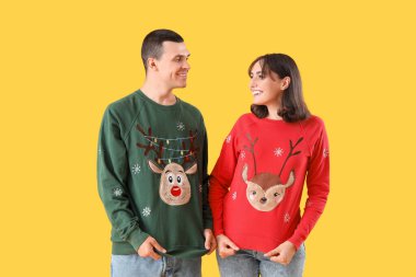 Sarı arka planda Noel elbiseli güzel bir çift.